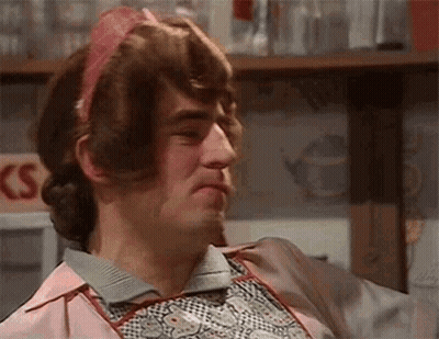 Man In Pink Apron And Wig Making Funny Face GIF