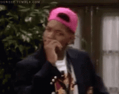 Man In Pink Baseball Cap And Suit Covering Mouth GIF