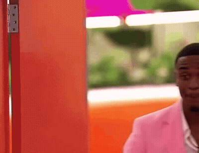 Man In Pink Jacket At Orange Door GIF