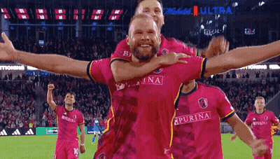 Man In Pink Purina Jersey Being Lifted By Another Man GIF