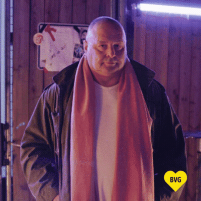 Man In Pink Scarf And Green Jacket With Yellow Heart Saying BG GIF