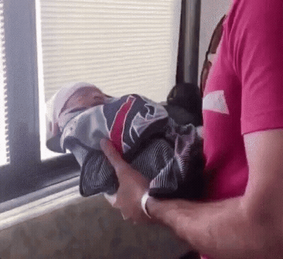 Man In Pink Shirt Holding Baby Wrapped In Jersey GIF