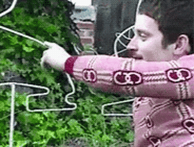 Man In Pink Shirt Holding Rope In Front Of Fence GIF