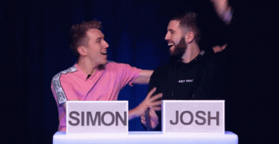 Man In Pink Shirt Next To Man In Black Shirt With Josh Sign GIF
