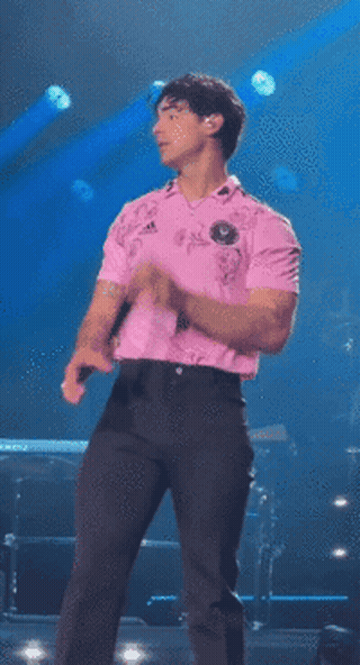 Man In Pink Shirt Singing Into Microphone On Stage GIF