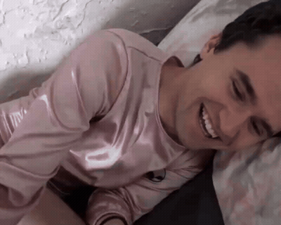 Man in Pink Shirt Smiling on Bed