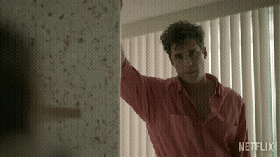 Man In Pink Shirt Standing By Netflix Window GIF