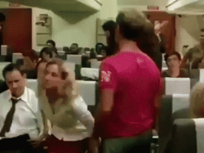 Man In Pink Shirt Standing In Front Of Group On Airplane GIF