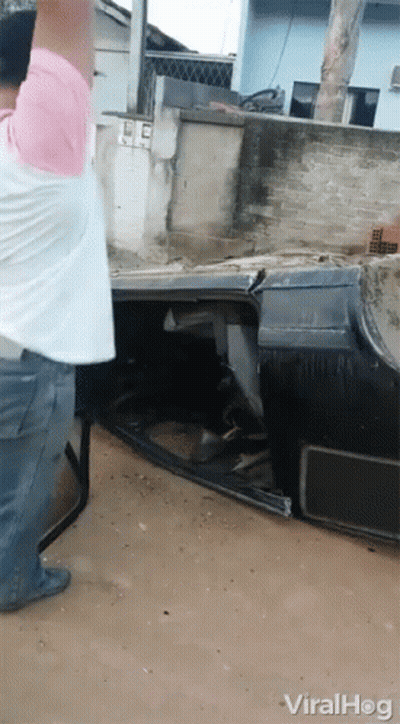 Man In Pink Shirt Standing Next To Crashed Car GIF