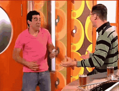 Man In Pink Shirt Talking To Man In Green And Black Striped Sweater GIF