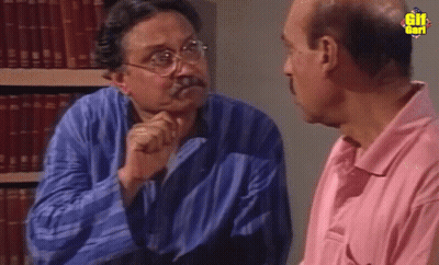 Man In Pink Shirt Talks To Man In Library GIF