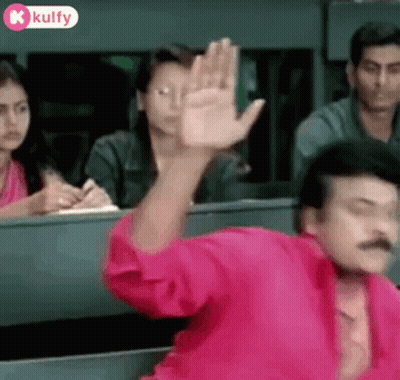 Man In Pink Shirt Waving In Classroom GIF