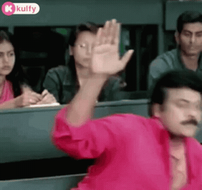 Man In Pink Shirt Waving To Group GIF