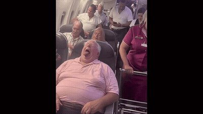 Man In Pink Shirt Yawning On Airplane GIF