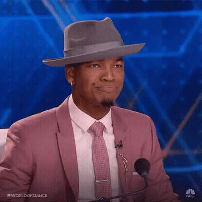 Man In Pink Suit And Tie Sitting At Microphone GIF