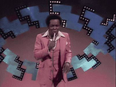 Man In Pink Suit Holding Microphone GIF