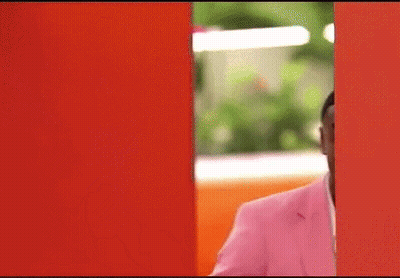 Man In Pink Suit Peeking Out Of Red Wall GIF