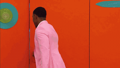 Man In Pink Suit Walking Through Doorway GIF