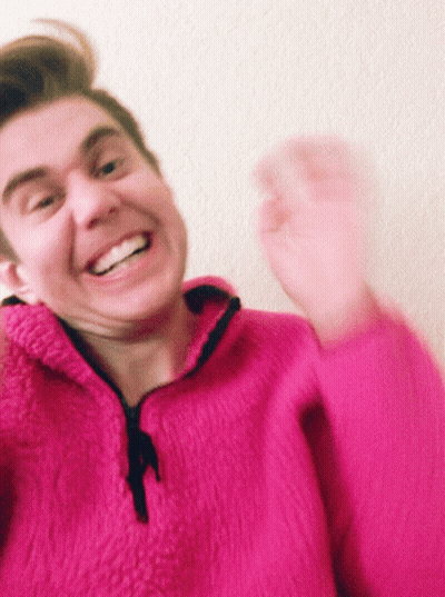 Man In Pink Sweater Smiling And Waving GIF