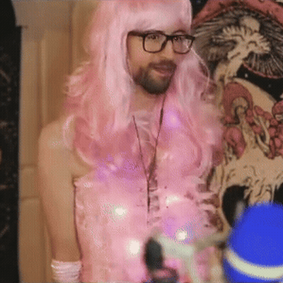 Man In Pink Wig And Glasses By Skull Wall GIF