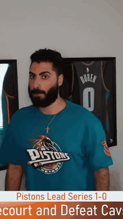 Man In Pistons T-Shirt In Front Of Framed Jersey GIF