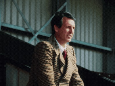 Man In Plaid Jacket And Tie Standing In Front Of Building GIF