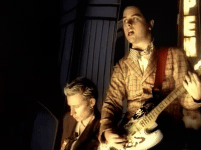 Man In Plaid Jacket Playing Guitar Beside Man In Suit GIF