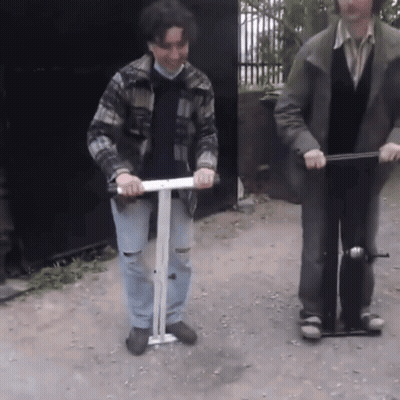 Man In Plaid Jacket Riding Scooter With Another Man GIF