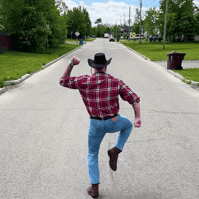 Man In Plaid Shirt And Cowboy Hat Standing On One Leg GIF