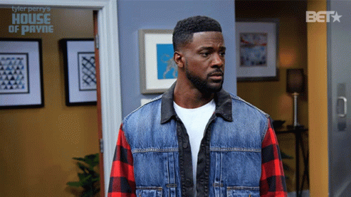 Man In Plaid Shirt And Denim Vest In Front Of House Of Payne Sign GIF