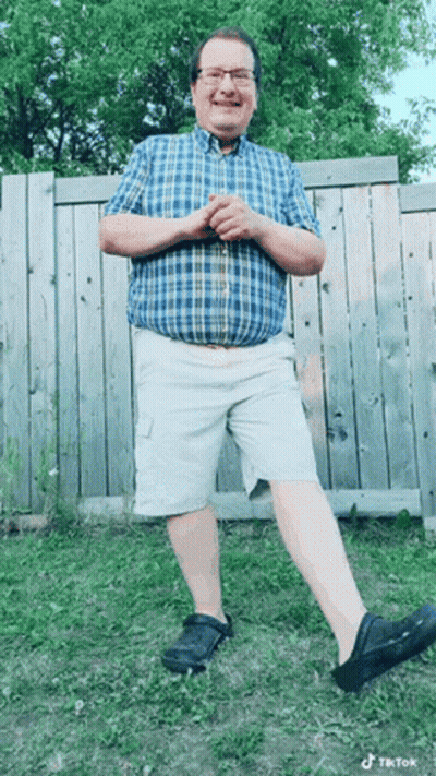 Man In Plaid Shirt And Shorts By Fence GIF
