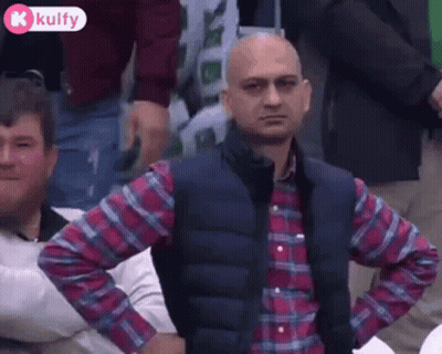 Man In Plaid Shirt And Vest With Hands On Hips In Crowd GIF