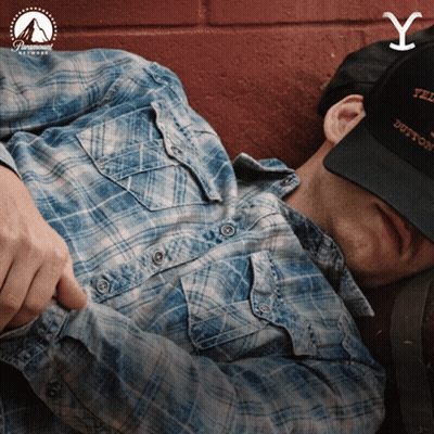 Man In Plaid Shirt And Yellowstone Hat Laying Down GIF