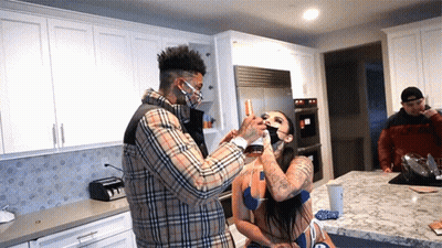 Man In Plaid Shirt Feeding Woman A Drink GIF