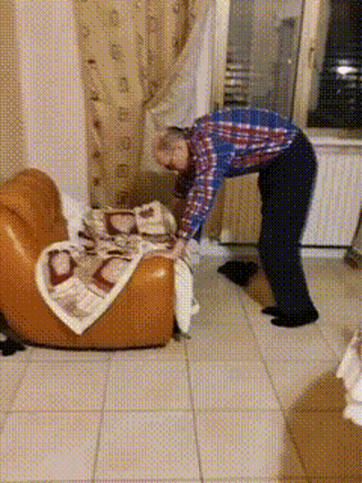Man In Plaid Shirt Folding Blanket On Chair GIF