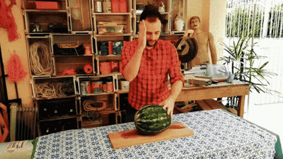 Man In Plaid Shirt Holding Head While Cutting Watermelon GIF