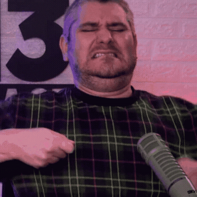 Man In Plaid Shirt Holding Microphone In Front Of Wall Number 3 GIF
