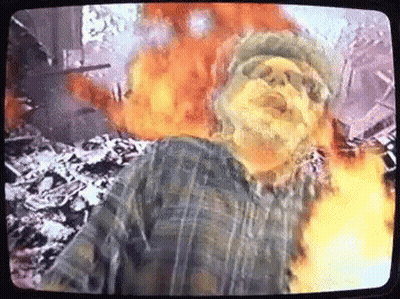 Man In Plaid Shirt In Front Of Fire Explosion On TV GIF