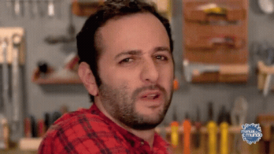 Man In Plaid Shirt Making Funny Face In Front Of Manual Del Mundo Sign GIF
