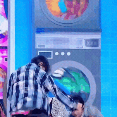 Man In Plaid Shirt Next To Washing Machines GIF