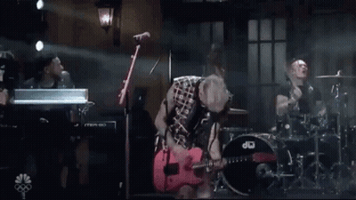 Man In Plaid Shirt Playing Red Guitar On Stage GIF