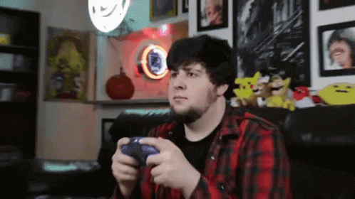 Man In Plaid Shirt Playing Video Game With PlayStation Controller GIF