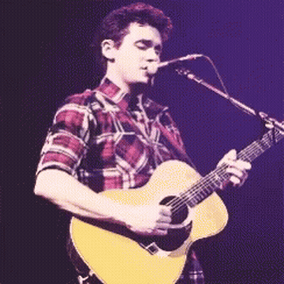Man In Plaid Shirt Singing Into Microphone Holding Guitar GIF