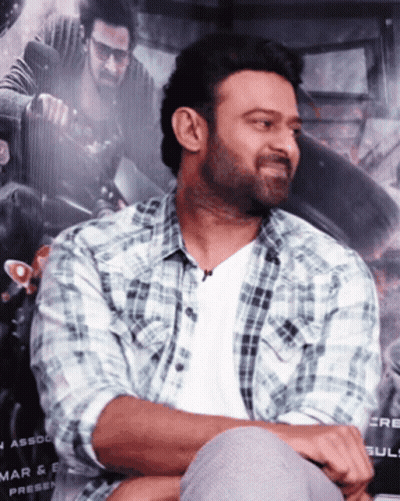Man In Plaid Shirt Sits In Front Of Mar & E Press Poster GIF