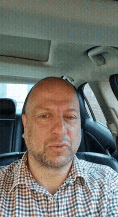 Man In Plaid Shirt Sitting In Car Looking At Camera GIF