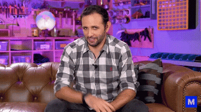 Man In Plaid Shirt Sitting On Couch With Blue M GIF