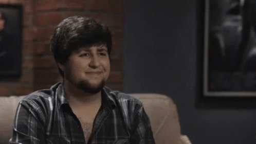 Man In Plaid Shirt Smiling In Front Of Poster GIF
