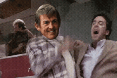 Man In Plaid Shirt Smiling While Man In Suit Laughing GIF