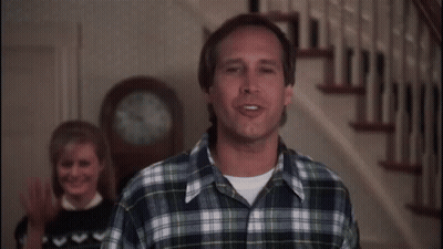 Man In Plaid Shirt Standing In Front Of Clock GIF