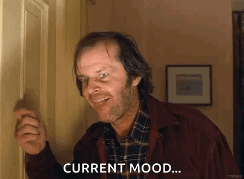 Man In Plaid Shirt Standing In Front Of Door Smiling GIF